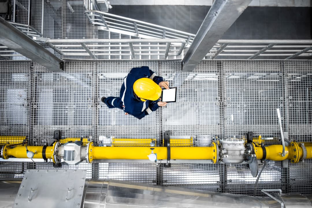 Trabajador inspeccionando tuberías sin costura de acero MMTubería en instalación petrolera